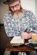 © Rawpixel.com - Man with beard writing in notebook at cafe table with coffee.