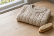 © Uniquecreations - Folded knit sweater with a clothing brush on a wooden table