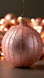 © Iryna - Sparkly cheer with a blush pink christmas ornament covered in glitter and water droplets, glowing against warm festive bokeh lights