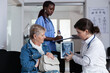 © DC Studio - Radiology, doctor and consultation with older woman reviewing cervical spine X-ray on tablet in hospital waiting area for scan discussion, patient education and medical care support.