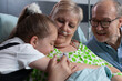 © DC Studio - Care, connection and affection in a close bedside moment as a senior patient holds the arm of a child in hospital, with an older man nearby for family support, comfort, recovery and togetherness.