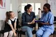 © DC Studio - Consultation, nurse and paperwork with woman and young girl reviewing clipboard in hospital waiting area, for communication, appointment guidance, patient support and care coordination.