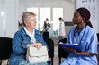 © DC Studio - Consultation, nurse and senior patient seated face to face in hospital waiting room as healthcare worker takes notes for medical assessment, communication, support and routine care.
