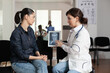 © DC Studio - Consultation, doctor and imaging with woman listening as physician explains diagnostic scan on tablet in hospital waiting area for patient education, medical communication, guidance and care support.