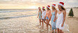 © Elena - Group of young women walking along the beach wearing Santa hats