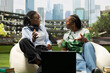 © DC Studio - College classmates, laptop and discussion focus on two women exchanging ideas while seated outdoors. Peer learning, collaboration and project planning support informal study on a green campus lawn.