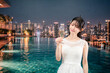 © maroke - ルーフトップのプールでドレスをてグラスを持つ若い女性