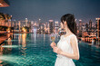 © maroke - ルーフトップのプールでドレスをてグラスを持つ若い女性