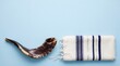 © NaesyaStudio - Traditional Jewish Shofar Ram Horn and Striped Tallit Prayer Shawl on Light Blue Background
