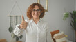 © Krakenimages.com - Woman giving thumbs up with visible thumb and white shirt in a cozy bedroom; optimism encouragement.