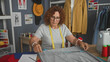 © Krakenimages.com - Woman measures grey fabric with tape measure and writes notes while hand supports chin in studio; concentration craft patience.