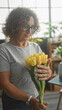 © Krakenimages.com - Woman with curly hair and glasses holds and adjusts a bouquet of yellow tulips with both hands in a bright studio; contentment care.