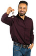 © fotofabrika - Man holding keys in his hand and smiling while wearing a burgundy shirt with jeans