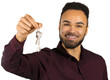 © fotofabrika - Man holding keys with a smile in a simple indoor setting