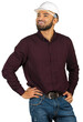 © fotofabrika - Worker in a hard hat smiling with hands on hips while wearing a button-up shirt and jeans