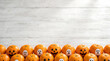 © Marlin crowell - Cute Halloween oranges with ghost faces drawn on peel sitting on white wood table with copy space