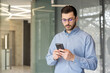 © Tetiana - Young businessman using smartphone in modern office building
