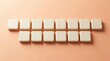© Tan - Minimalist arrangement of beige square tiles in ordered rows on a soft peachy background