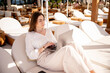 © ADDICTIVE STOCK - Businesswoman working remotely on laptop at seaside cafe