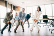 © deagreez - Group of business professionals engaged in dynamic team-building exercises in a modern office space