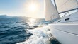 © Bonsales - Sailboat gliding across blue water and throwing a foamy wake beneath white sails, with sunlight shimmering over a distant mountain coast