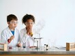 © Danawan Purbanggoro - Curious young students in lab coats and safety goggles react with shock and amazement during a chemical experiment in a science room, sparking discovery and wonder.