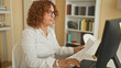 © Krakenimages.com - Woman holding document and tapping keyboard while pointing and giving a thumbs up at computer in office building; confidence.