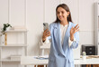 © Pixel-Shot - Video call communication and remote work, smiling woman waving hand during online meeting on smartphone in modern office