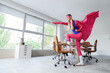 © Pixel-Shot - Empowerment and workplace productivity, woman in superhero costume with cape standing on office chair to achieve goals and success in corporate environment