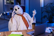 © Pixel-Shot - Burnout and workplace stress, tired employee in ghost costume working late on laptop with deadline pressure in dark office at night