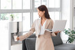 © Pixel-Shot - Workplace break and office hydration, businesswoman with laptop getting water from cooler during busy workday in modern corporate environment
