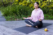 © Wavebreak Media - Woman in pink hoodie meditating cross-legged on dark yoga mat beside lit candle on wooden deck