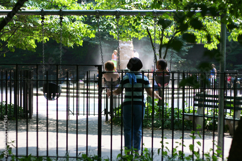 2 kids with grownup on playground swings