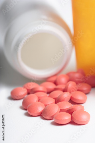 spilled pile of red tablets beside two medicine bo