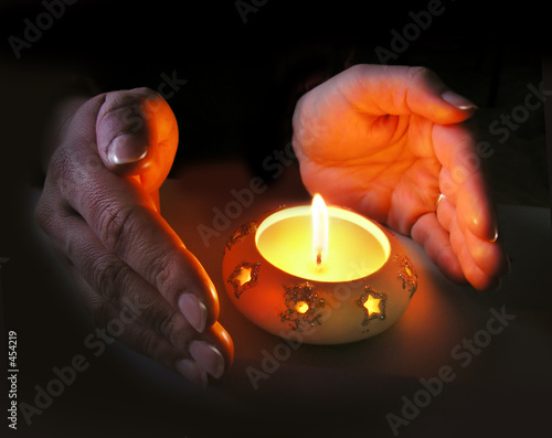 woman's hands lit by a christmas candle