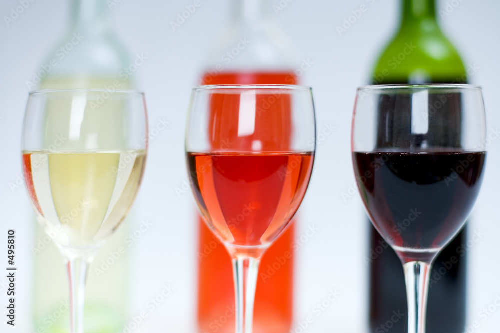 red, white and rose wine in glasses with bottles behind red, white and rose wine in glasses with bottles behind
