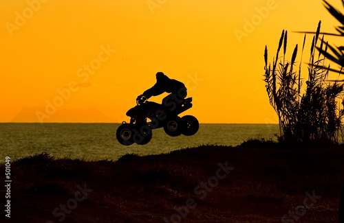quad bike jumping on beach at sunset in spain