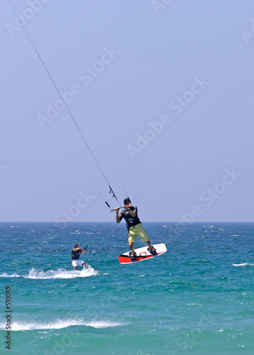 kitesurfer flying through the air on a sunny beach