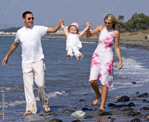 young family playing with daughter on beach in spain