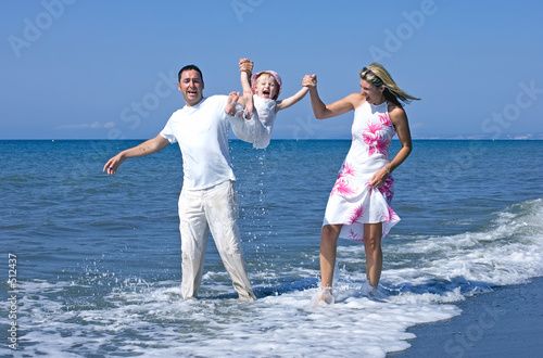 young family playing with daughter on beach in spain