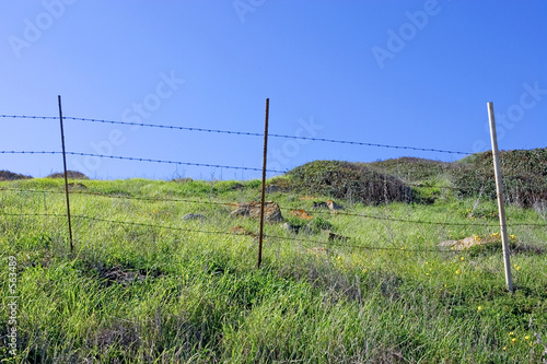 old fence and green fields with deep blue sky
