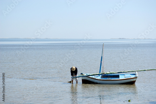 fisherman in straw hat preparing boat to sail out