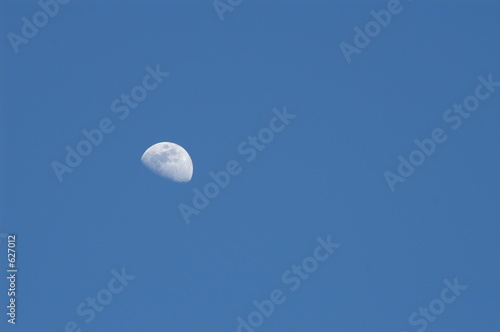 three quarter moon on medium blue sky