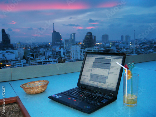 laptop in rooftop bar with sunset photo