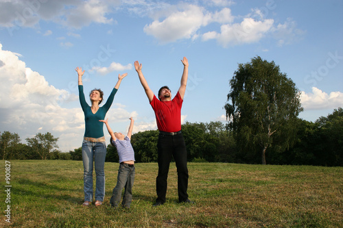 family with hands up on meadow