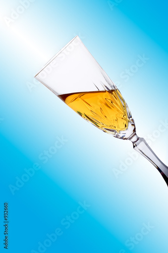 glass filled with white wine against blue backgrou