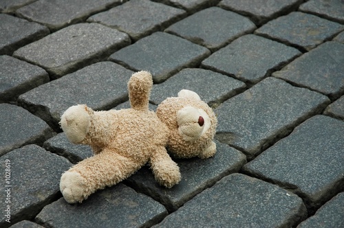 little teddy-bear laying on the cobblestones