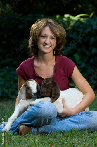 smiling young woman with a pair of baby goats