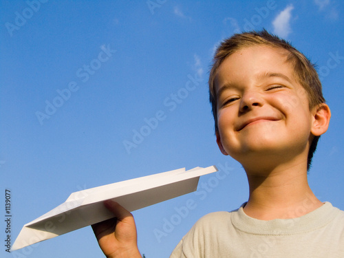 a smiling boy with a paper aeroplane toy