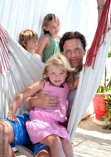 young father and children sitting in a hammock on vacation